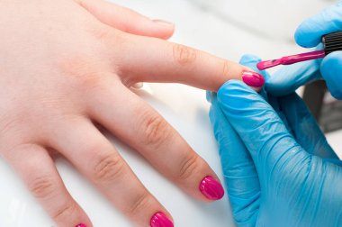 Manikür tırnak boya pembe renk. Tırnak bakımı. Spa salonunda manikür yaptıran güzel kadın ellerinin yakın çekimi. Profesyonel manikür ile kadın manikürcü temizlik kütikül. Kozmetik prosedür.