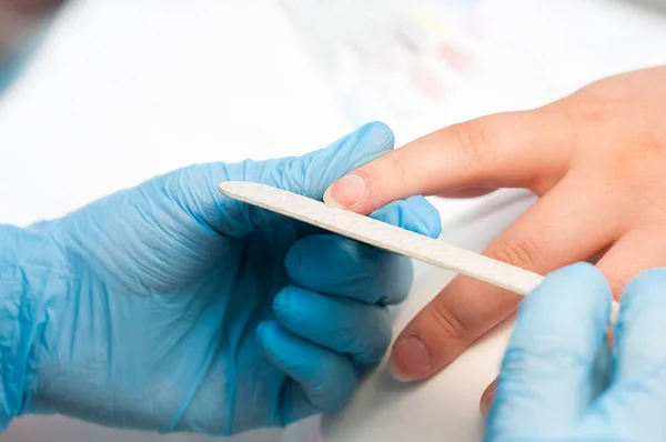 Closeup çekim tarafından bir güzellik tırnak törpüsü ile manikür alma bir tırnak salonu içinde bir kadın. Kadın Başlarken tırnak manikür. Şevval Özçelik Güzellik dosya bir müşteriye çivi.