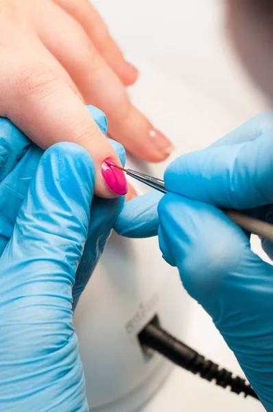 Manikür tırnak boya pembe renk. Tırnak bakımı. Spa salonunda manikür yaptıran güzel kadın ellerinin yakın çekimi. Profesyonel manikür ile kadın manikürcü temizlik kütikül. Kozmetik prosedür.