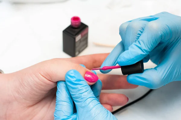 Manikür tırnak boya pembe renk. Tırnak bakımı. Spa salonunda manikür yaptıran güzel kadın ellerinin yakın çekimi. Profesyonel manikür ile kadın manikürcü temizlik kütikül. Kozmetik prosedür.
