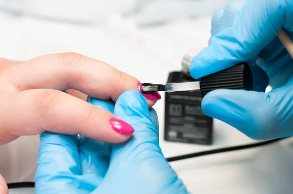 Manikür tırnak boya pembe renk. Tırnak bakımı. Spa salonunda manikür yaptıran güzel kadın ellerinin yakın çekimi. Profesyonel manikür ile kadın manikürcü temizlik kütikül. Kozmetik prosedür.