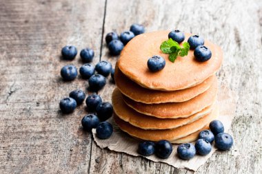 Ahşap masa üzerinde taze yaban mersini ile viski krep yığını 