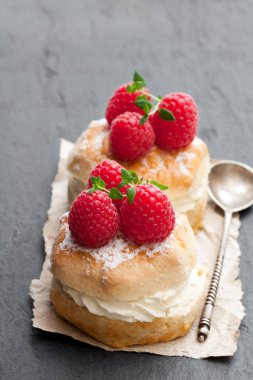 Ahududu ve siyah taş zemin üzerine krema ile geleneksel çörekler 