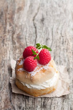 Ahududu ve ahşap masa üzerinde krema ile geleneksel çörekler 