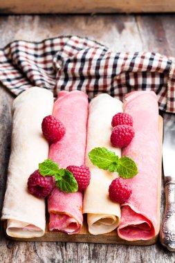 Haddelenmiş süt ve ahududu krep yerken üzerine ahşap masa 