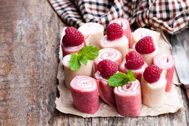 Haddelenmiş süt ve ahududu krep yerken üzerine ahşap masa 