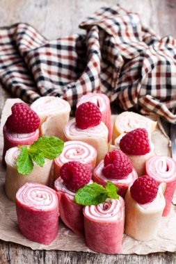 Haddelenmiş süt ve ahududu krep yerken üzerine ahşap masa 