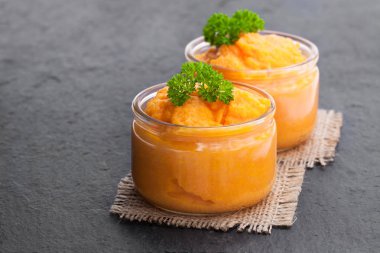 Carrot  puree in glass jars on black stone background  clipart