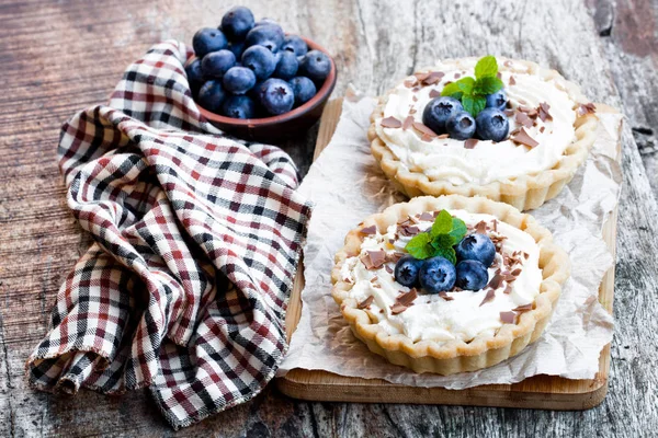 木製のテーブルにクリームと新鮮なブルーベリーと美味しいタルト — ストック写真