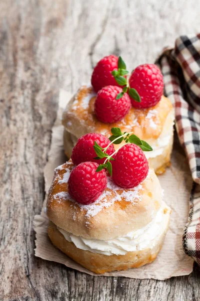 Ahududu ve ahşap masa üzerinde krema ile geleneksel çörekler 