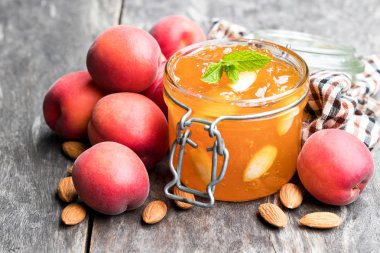 Ahşap masa üzerinde açık cam kavanozda Bademli kırmızı Kayısı reçeli 