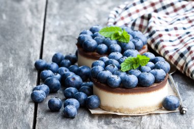 Ahşap masa üzerinde taze yaban mersini ile iki mini çikolata cheesecake 