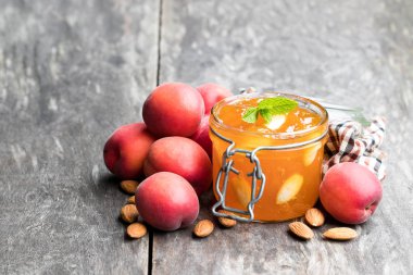 Ahşap masa üzerinde açık cam kavanozda Bademli kırmızı Kayısı reçeli 