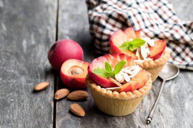 Taze kırmızı kayısı ve badem ahşap masa üzerinde yumurta kremalı tart 