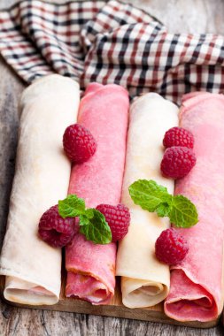 Haddelenmiş süt ve ahududu krep yerken üzerine ahşap masa 