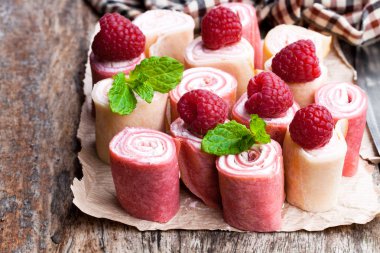 Haddelenmiş süt ve ahududu krep yerken üzerine ahşap masa 