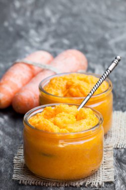 Carrot  puree in glass jars on wooden table  clipart