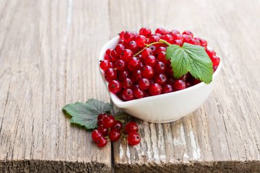 Ahşap masa üzerinde seramik kase taze kırmızı kuş üzümü 