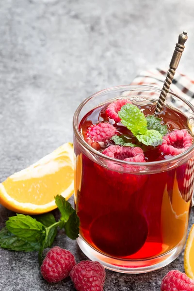 Red fruit  tea with raspberry and orange on gray table