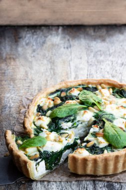 Beyaz peynir ve ahşap masa üzerinde çam fıstığı ile vejetaryen ıspanak tart 