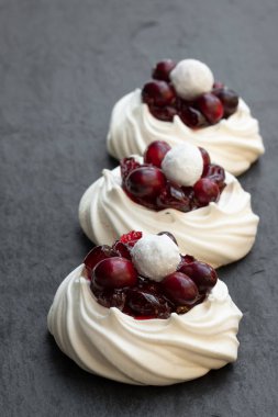 Mini Pavlova beze yuva ile siyah taş zemin üzerine taze ve şekerli kızılcık 