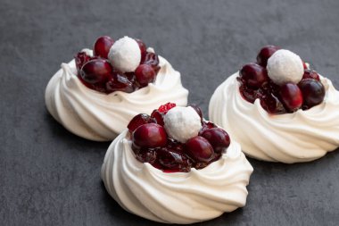 Mini Pavlova beze yuva ile siyah taş zemin üzerine taze ve şekerli kızılcık 