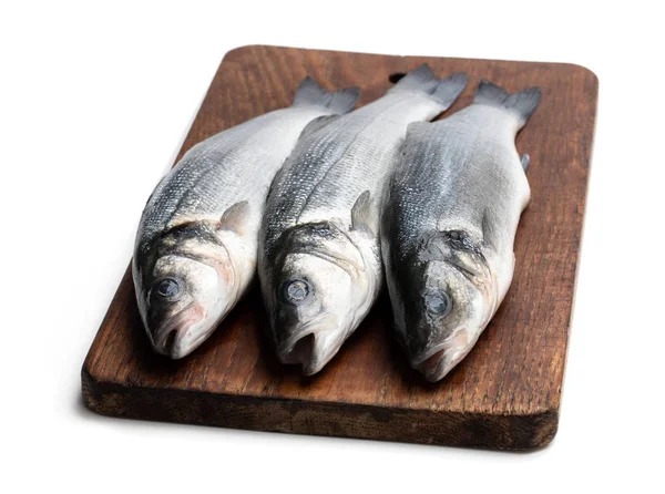 新鲜的整个海低音鱼在切菜板上查出在白色 — 图库照片