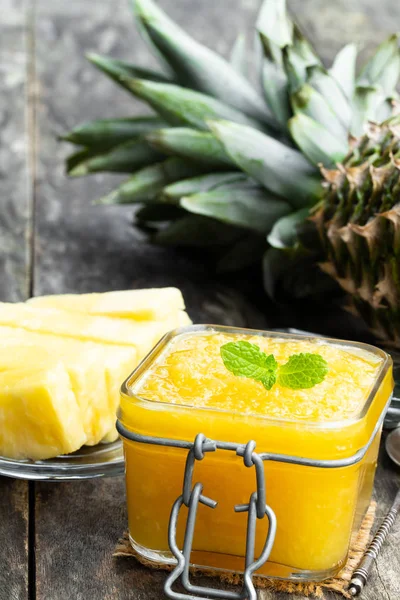 Homemade pineapple jam in glass jar on wooden table