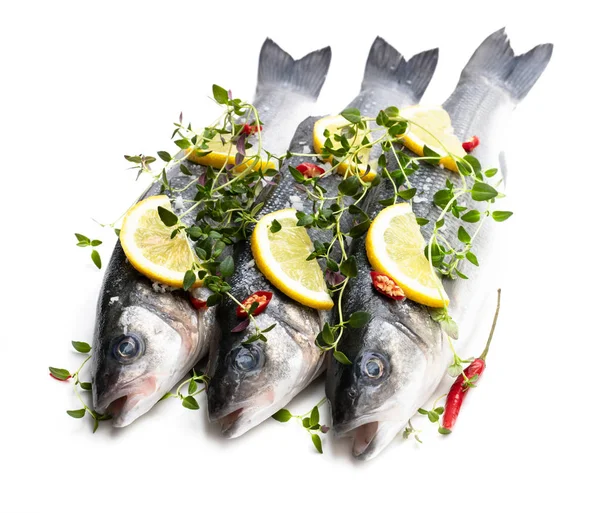 Pesce branzino intero fresco con limone e spezie isolato su un bianco — Foto Stock