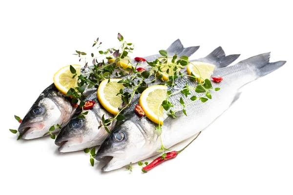 Pesce branzino intero fresco con limone e spezie isolato su un bianco — Foto Stock