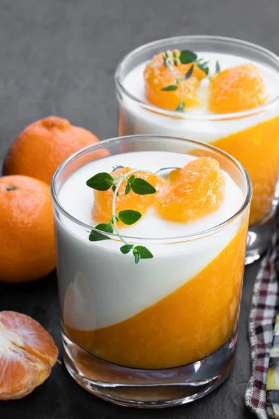 Panna cotta com geleia de mandarina em vidro transparente sobre fundo de pedra preta — Fotografia de Stock