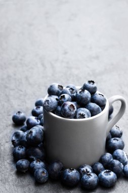 Siyah taş arka planda taze olgun yaban mersini dolu fincan 