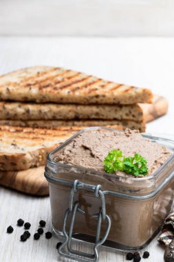 Beyaz ahşap masada tost ekmeği ile cam kavanozda taze pate 