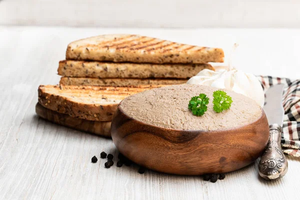 Свежий паштет с жареным хлебом на белом столе — стоковое фото