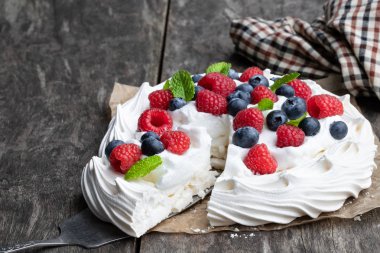 Ahşap masa üzerinde çilek ve nane yaprakları ile Pavlova beze yuva 