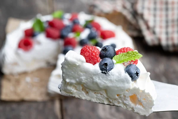 Pavlova felie de meringue cu fructe de padure si frunze de menta pe masa de lemn — Fotografie, imagine de stoc