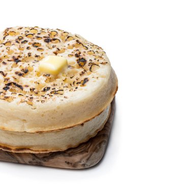 Beyaz üzerine izole kesme tahtası üzerinde eritilmiş tereyağı ile dev crumpets 