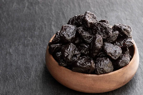 Küçük ahşap plaka kurutulmuş erik dolu masada izole 