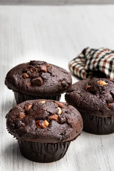 Trzy czekoladowe muffinki na rustykalny stół z tkaniną serwetką — Zdjęcie stockowe