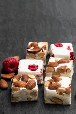 Siyah taş arka plan üzerinde badem ve kurutulmuş meyve ile ev yapımı nougat barlar 