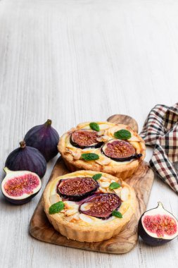 Krem peynirli ev yapımı incir kaplumbağaları ve beyaz ahşap masada badem. 