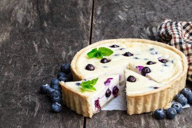 Kırsal ahşap masada yaban mersinli cheesecake. Yaz tatlısı 