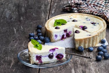 Kırsal ahşap masada yaban mersinli cheesecake 