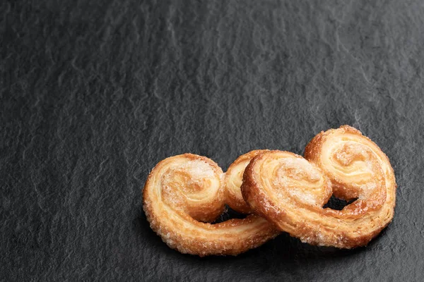 Karamelli şekerle kaplanmış yumuşak kalpler siyah taş arka planda. 