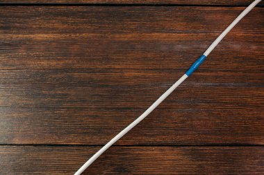 Hasarlı LAN kablosunu koyu ahşap bir arka planda yalıtkan bantla tamir ettim. Gücün ve iletişimin restorasyonu 