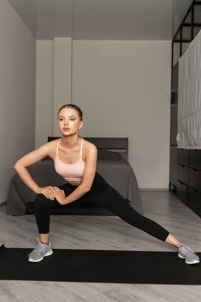 Spor giyimli beyaz kadın antrenmana başlamadan önce bacaklarını paspasın üzerine uzatıyor. sağlık hizmeti kavramı.