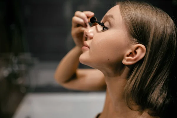 Hermosa mujer caucásica pinta pestañas en el baño. Primer plano. Belleza femenina — Foto de Stock