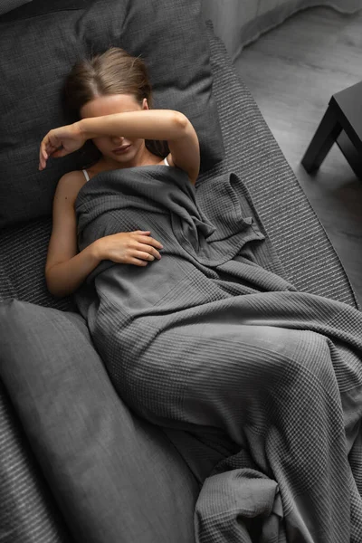 Belle femme caucasienne se réveille le matin sur le canapé à la maison et se frotte les yeux sans dormir. — Photo