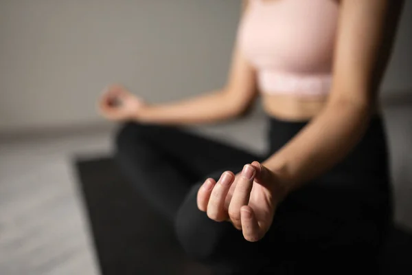 Spor giyim bölümünde beyaz güzel bir kadın evdeki minderde yoga yapıyor. Kapat elini.