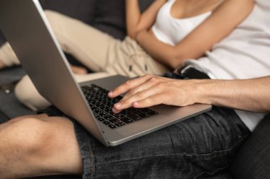 Adamın biri dizüstü bilgisayarında koltukta oturan bir kızın yanında bir şey yazıyor.